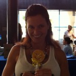 Woman holding a Sudsies smiley cookie in a bright event space