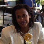 Woman in white jacket holding a Sudsies smiley cookie