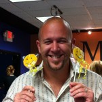 Smiling man holding two Sudsies smiley cookies at event