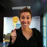 Smiling woman holding a wrapped Sudsies smiley cookie