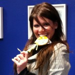 Woman smiling while holding a Sudsies smiley cookie