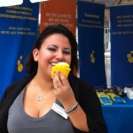 Woman smiling with yellow cupcake at Sudsies event booth