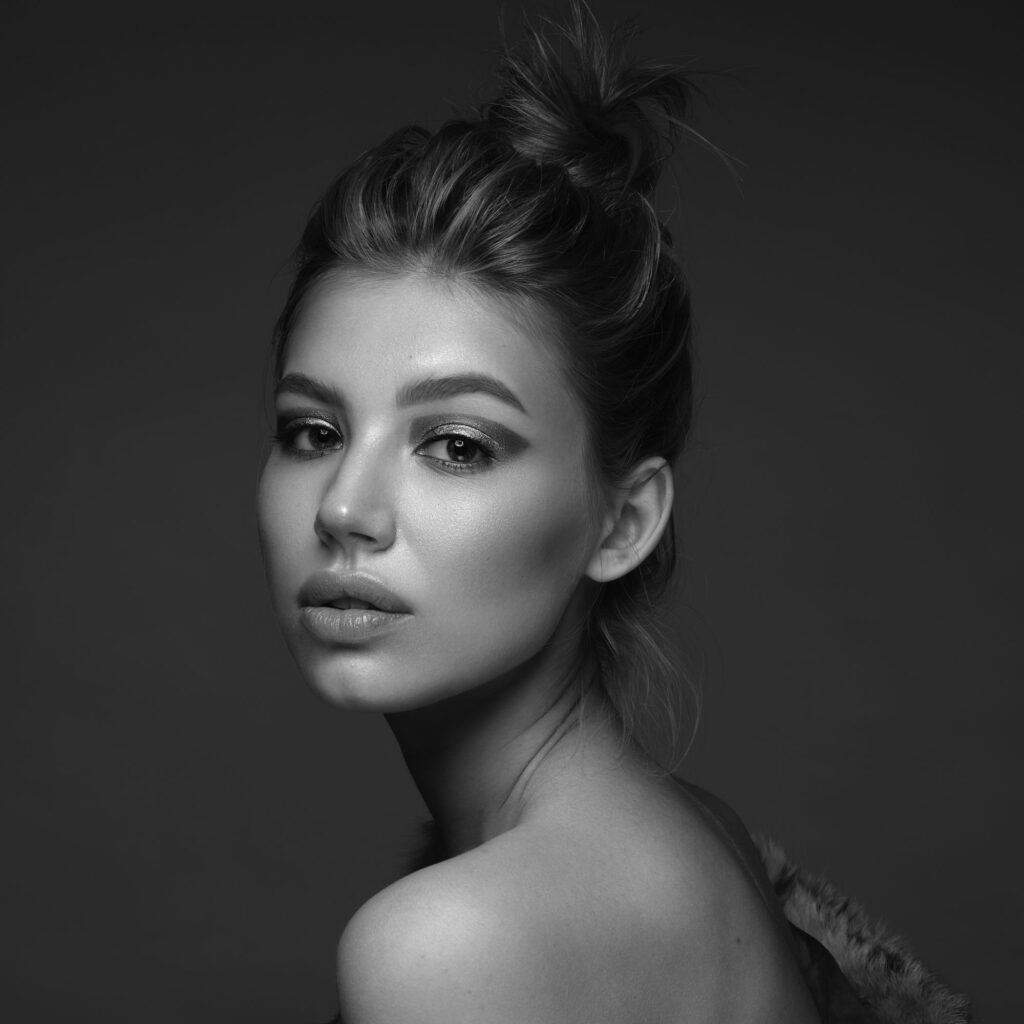 Black-and-white studio portrait of a woman wearing a textured fur-trim garment