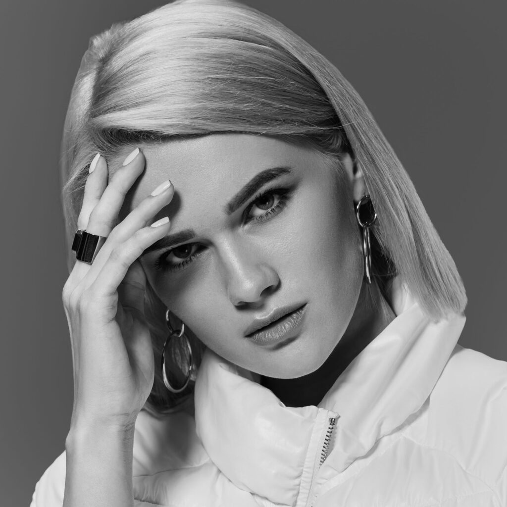 Black-and-white fashion portrait of a woman wearing a structured high-collar jacket